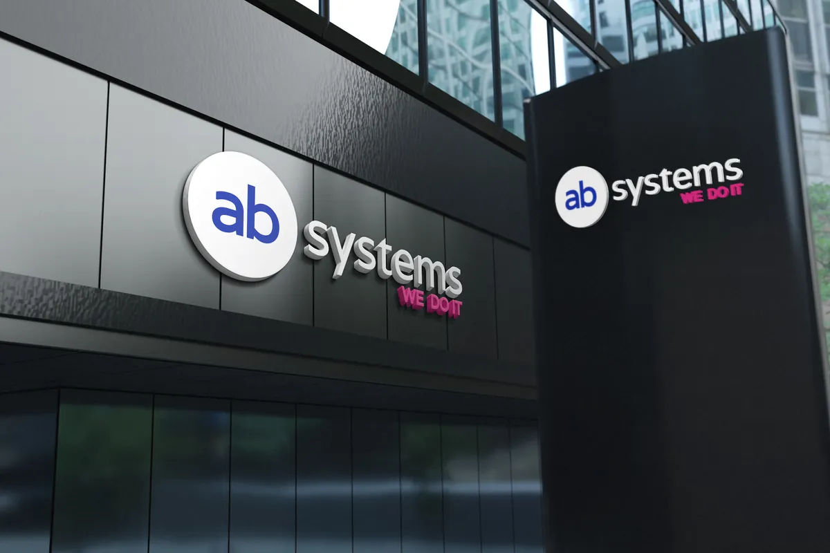 AB Systems: przestrzenne logo z różowym hasłem WE DO IT na czarnej elewacji i pylonie przed budynkiem