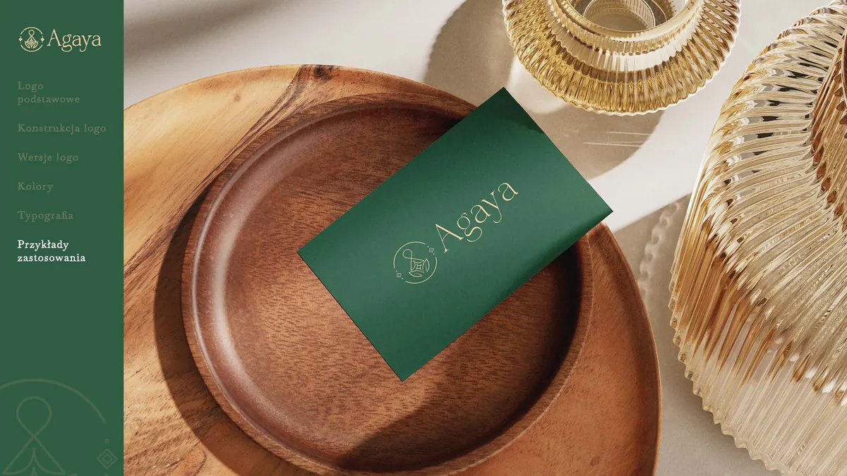 Agaya: green business card with a beige logo on a wooden plate next to golden glass vessels