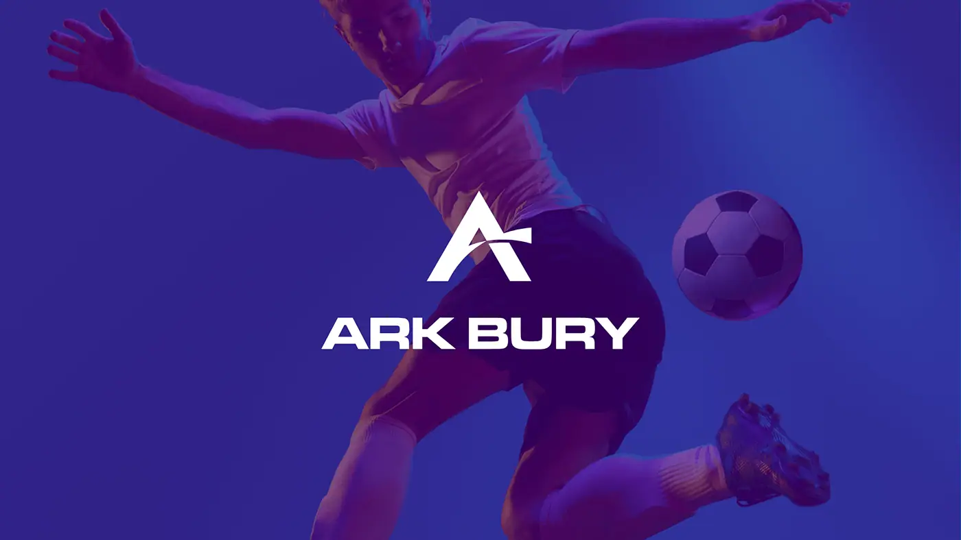 Ark Bury: białe logo z sygnetem A na fioletowym zdjęciu piłkarza kopiącego piłkę