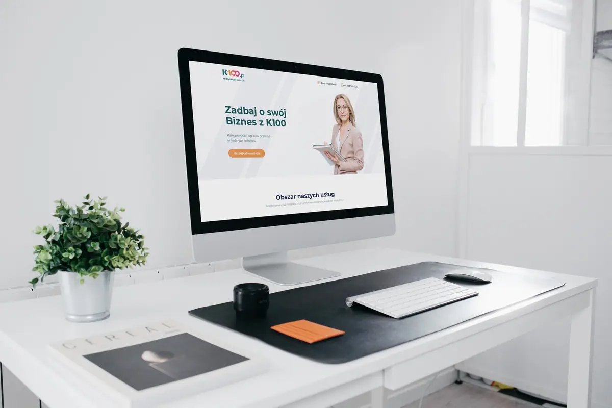 K100: landing page z hasłem Zadbaj o swój Biznes z K100 na monitorze w jasnym biurze