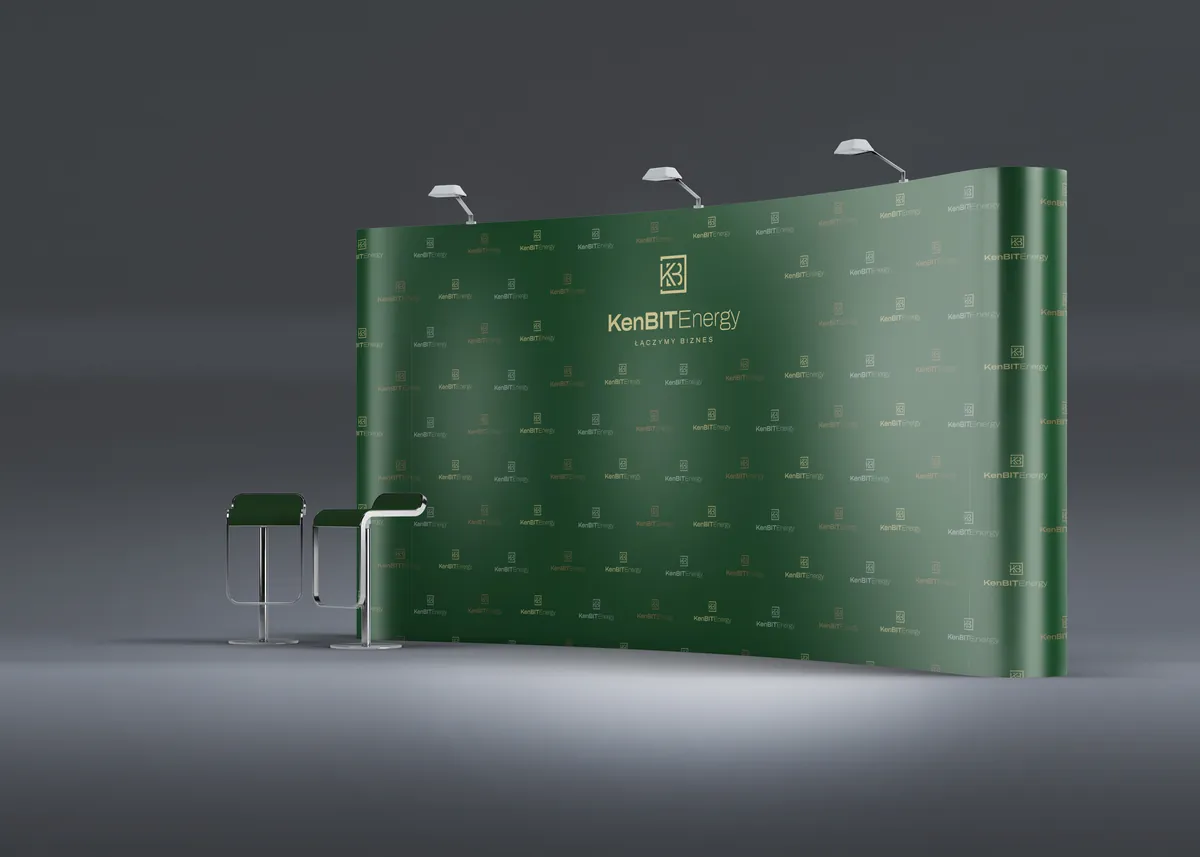 KenBIT Energy: zielona ścianka reklamowa z logo, trzema lampami i hokerami na grafitowym tle, ujęcie z ukosa