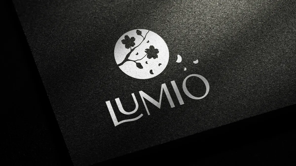 Lumio: srebrne logo z sygnetem gałązki tłoczone na czarnym papierze z fakturą