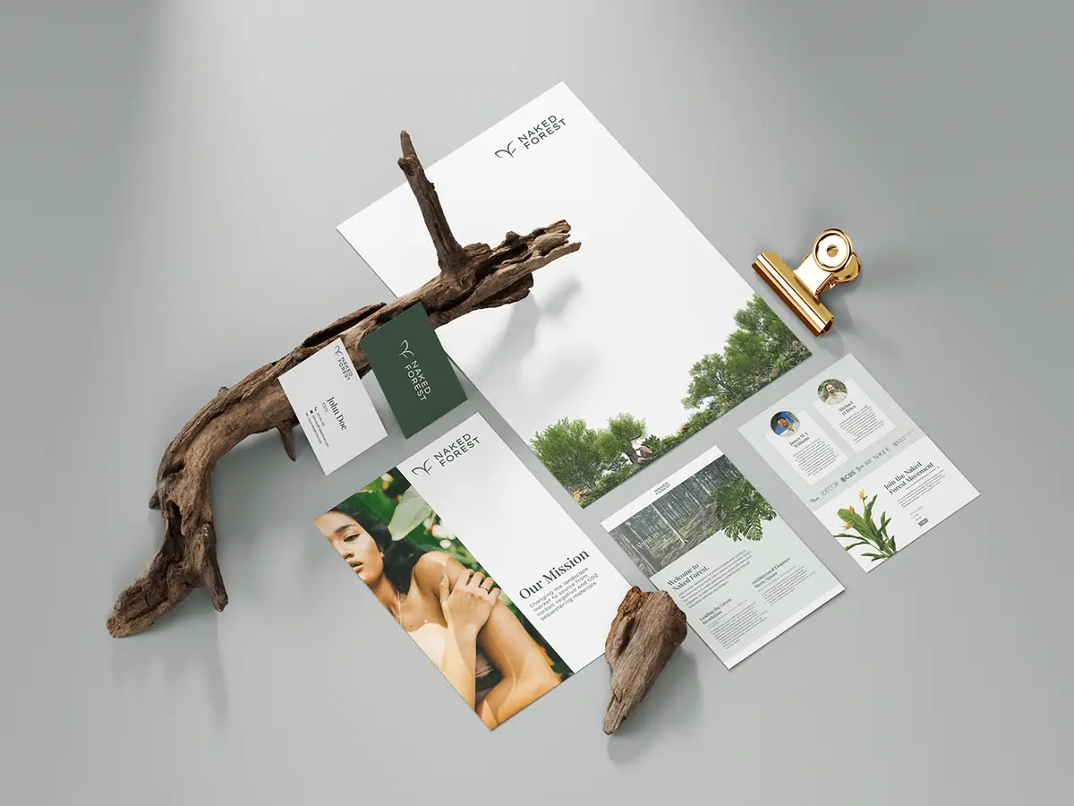 Naked Forest: wizytówki, papier firmowy i ulotki w bieli i zieleni ułożone z kawałkami drewna
