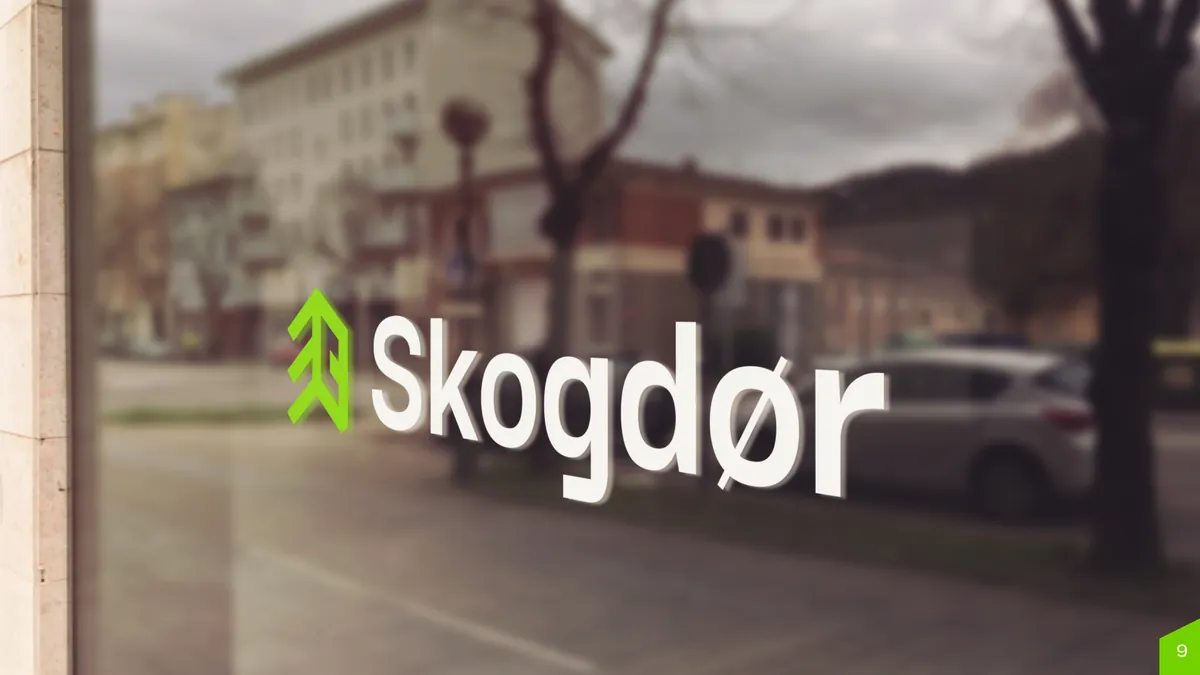 Skogdor: białe logo z zielonym sygnetem na szybie witryny, w tle rozmyta ulica
